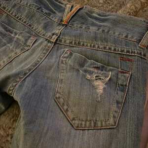 Blåa Jeans med hål lågmidjade - Supersnygga lågmidjade stl 34, saknar en knapp.