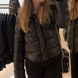 Svart pufferjacka - Snygg svart pufferjacka från Superdrymed glansig yta. En stilren och trendig jacka som funkar till många olika outfits. Den har en liten defekt vid fickan men inget man tänker på, kan skicka bild om så önskas. Använd men i gott skick. Köpt för 1500kr säljer för 1000