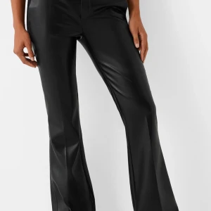 Svarta skinnbyxor från Bershka - Snygga svarta skinnbyxor från Bershka med låg midja och bootcut. Perfekta för en trendig look med en glansig finish. Säljer då dem tyvärr inte passade mig i längd och jag är 164cm. Innebenslängden är 84cm. Dem är ”varma” på insidan