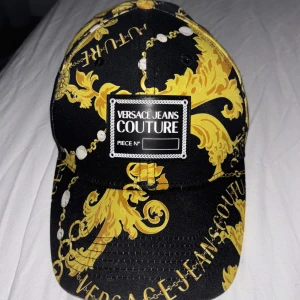 Versace Jeans Couture keps - Snygg och sällsynt keps från Versace Jeans Couture. Perfekt för att ge din outfit en lyxig touch. Köpt från vestiare collective. Hör av dig om du har frågor!