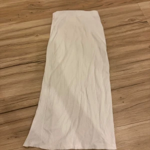 Vit ribbad kjol - Säljer en stilren vit ribbad kjol i lång modell. Perfekt för en minimalistisk look.