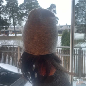 Grå stickad mössa från & Other Stories - Snygg och enkel grå stickad mössa från & Other Stories. Perfekt för kyliga dagar med sin mjuka och bekväma passform. Ett stilrent val för både vardag och utflykter.