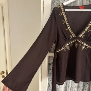 Brun blus från s.Oliver - Säljer en elegant brun blus från s.Oliver med vackra broderade detaljer i guld och beige. Blusen har långa ärmar och en v-ringad design! Påminner lite om blisen från Nelly! Står att den är stl 44 men enligt mig så passar den en stl S