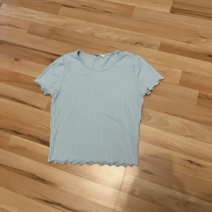Ljusblå ribbad topp - Säljer en söt ljusblå ribbad topp med korta ärmar och vågig kant.