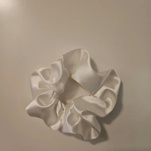 Vit satinscrunchie i storlek "L" - Egensydd fin gkansig vit scrunchie i ett satinliknande polyestertyg, resårsnöre på insidan.  Scrunchie storlek "L". Se exempelbild för jämförelse!  Hittar du inte en scrunchie i den färg du vill ha? Jag har flera scrunchies i olika färger/tyger, skicka bara ett meddelande!