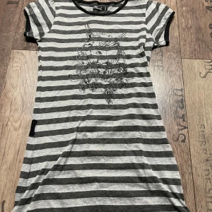 Grå och svart randig topp från 06Soul - Säljer en grå och svart randig topp från 06Soul med ett glittrigt tryck framtill. Toppen har korta ärmar och en rund halsringning med svart kant. Perfekt för en avslappnad stil.