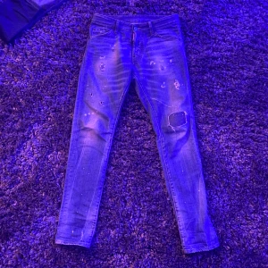   Dsquared2 Jeans - Snygga blå jeans från Dsquared2 med slitna detaljer och en patch på ena benet. Perfekt för en trendig look med en tight passform. Pris går att diskutera.(äkta) ny pris ca 6500kr