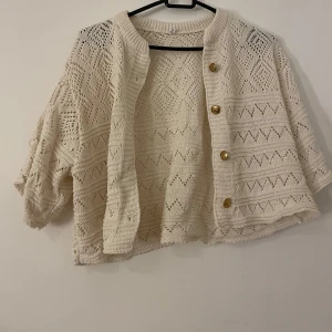 Beige stickad kofta med knappar - Säljer en söt beige stickad kofta med korta ärmar och fina mönster. Passar 36-38. Använd en gång. 