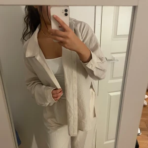 Beige långärmad skjorta -  Beige långärmad skjorta med knappar framtill. Oanvänd. Storlek 36-40. Är ett set