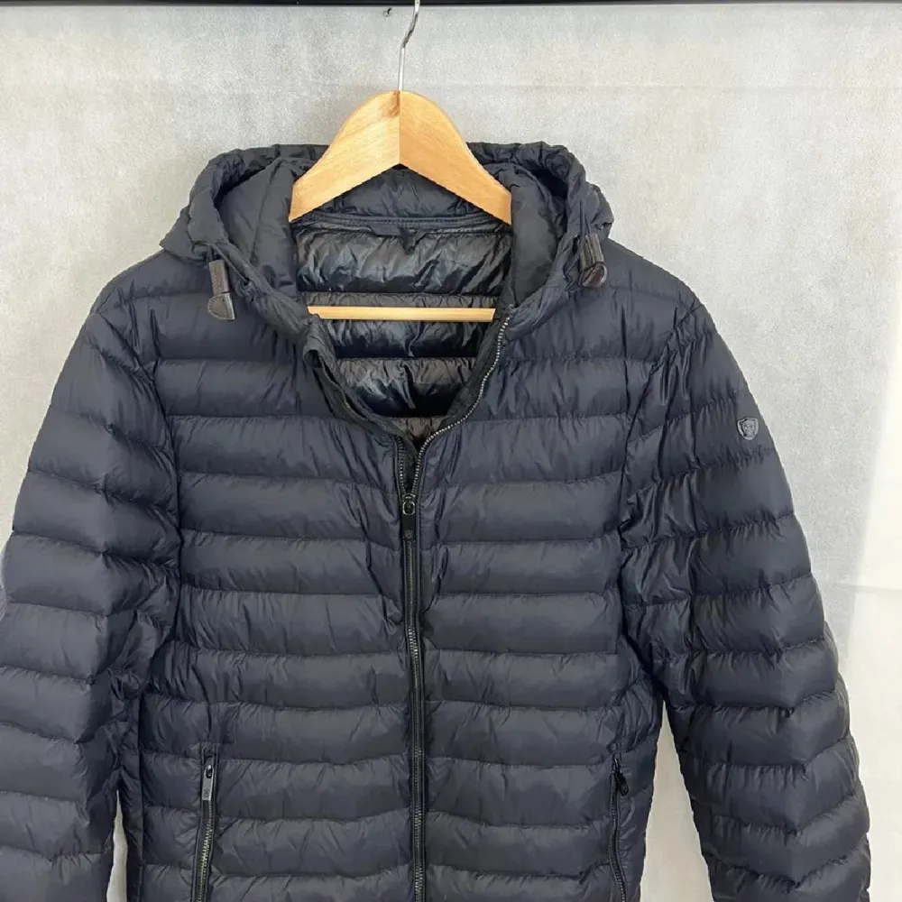 Snygg mörkblå pufferjacka med huva och dragkedja framtill. Jackan har en quiltad design och är perfekt för kyligare väder. Den har långa ärmar och en stilren look som passar till det mesta. Inga stora skador , 8/10 skick, pris går alltid att diskuter! ✅. Takit.