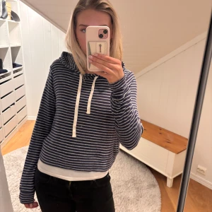 Blå och vit randig hoodie från Hollister  - Säljer en snygg blå och vit randig hoodie från Hollister. Den har en justerbar dragsko i huvan och långa ärmar. Perfekt för en avslappnad stil. Jag är från Norge och kan ta betalt gjennom vipps 