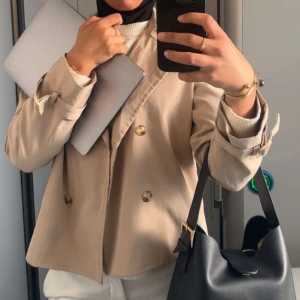 Beige kavaj med knappar - Snygg beige kavaj med dubbelknäppning och klassisk design. Perfekt för en stilren look. Passar bra till både vardag och mer formella tillfällen.