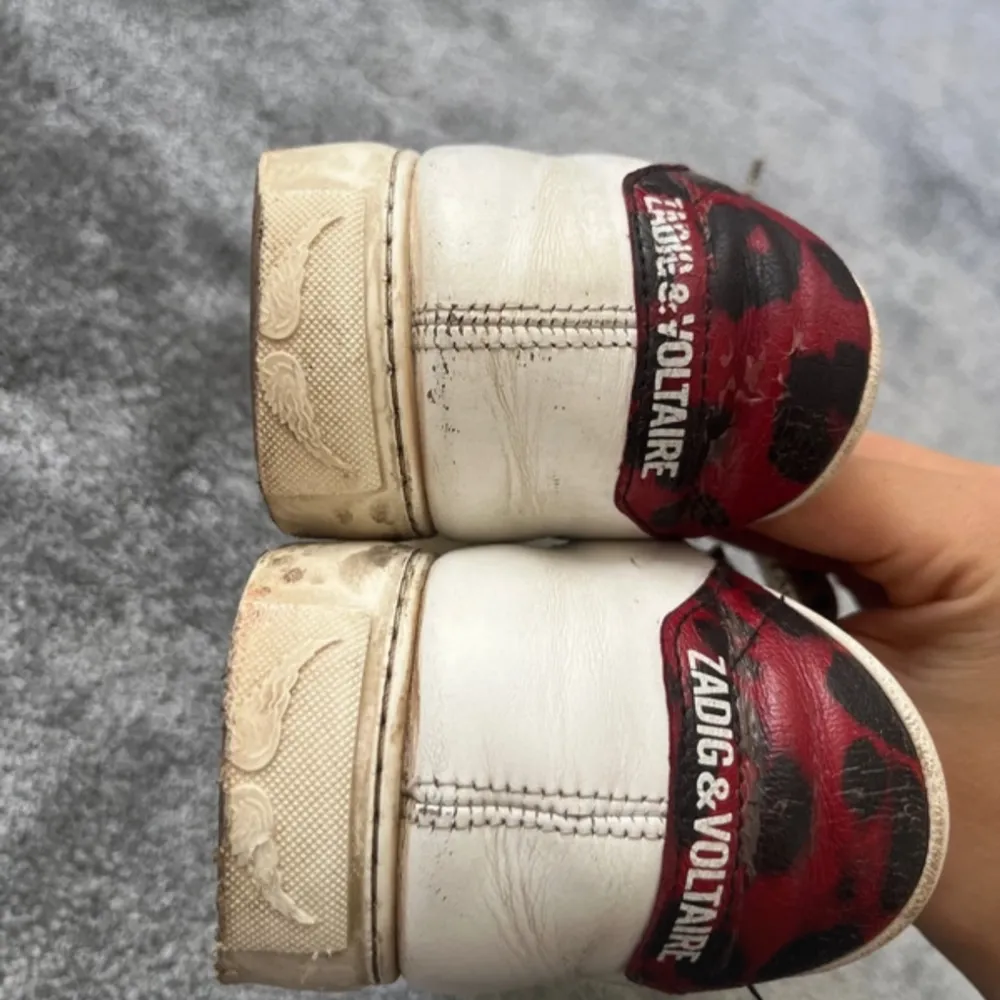 Snygga vita sneakers med leopardmönstrade detaljer i rött och svart från Zadig & Voltaire. De har några defekter, de sista 2 bilderna. Men det är varken något som syns eller känns. Box och dustbag medföljer. Nypris är 4000. Kengät.