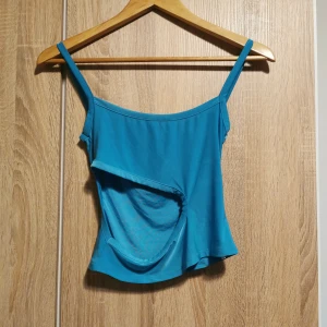 (S) Tight glansigt blått linne /topp - Snyggt blått glansigt linne i 36/S. Stor öppning för hud på ena sidan. Egentligen gick ena bandet mycket längre och skulle runt nacken, så har själv justerat så de matchar i längd (se sista bilden) 💙. 