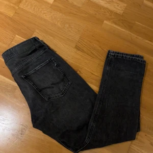 Svarta jeans från Jack & Jones - Säljer ett par svarta jeans från Jack & Jones i modellen Loose/Chris. De har en loose passform och är tillverkade i ett slitstarkt material. Perfekta för en avslappnad stil. Den har också slitits vid märken där bak därför jag kan gå ner lite vid snabb affär.                                                                       TAR EMOT BYTEN