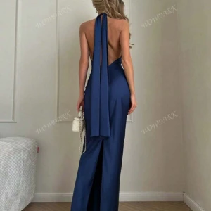 Mörkblå balklänning med öppen rygg - Elegant mörkblå klänning i satin med en stilren halterneck-design och öppen rygg. (Perfekt till bal) Klänningen har en smickrande passform och en slits som ger extra rörelsefrihet. Perfekt för en glamorös kväll.