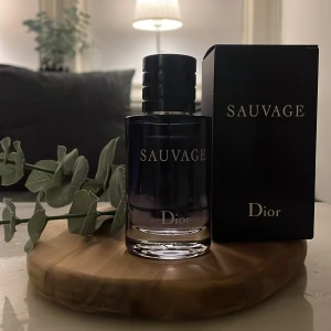 Sauvage parfym från Dior - Säljer en elegant parfymflaska av märket Dior, modell Sauvage. Flaskan är mörk med en stilren design och har en svart kork med Diors logotyp på toppen. Perfekt för den som söker en manlig och somrig doft. Den har ungefär 55 ml kvar av 60 fråga om det är något. OBS det är eue de toilett versionen pris kan självklart diskuteras 