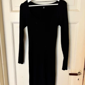 Svart långärmad klänning - Snygg svart långärmad klänning med en figurnära passform. Perfekt för en stilren look. Klänningen har en enkel design som gör den lätt att matcha med olika accessoarer.