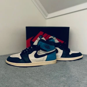 Nike Air Jordans i svart, vit och blå - Snygga Nike Air Jordans i en cool färgkombination av svart, vit och blå. Skorna har klassisk snörning och en ikonisk design som passar perfekt för sneakerheads. Perfekta för att lyfta din stil till nästa nivå.