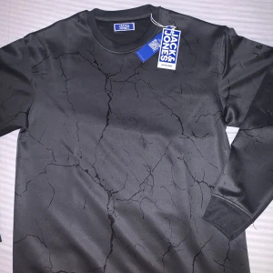 Träningströja från Jack & Jones - Snygg svart tröja från Jack & Jones med ett unikt krackelerat mönster. Tröjan har långa ärmar och en rund halsringning, perfekt för en stilren look när du tränar eller så! Jag säljer den för att den är för stor och nypris är 449 men jag säljer 399! Pris går att diskutera! Den är använd 0 gånger och är fof i nyskick 10/10, lappen kvar!🔥Hör av er vid minsta fundering!😊