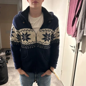 Mörkblå stickad cardigan med luva - Tja, säljer min blåa cardigan som är otroligt varm och bekväm. Perfekt för sen vinter och ända inpå våren. Använd lite under vintern men annars knappt någonting, skick 8/10. Modellen på bilden är 183 cm och 75 kg. Den är true to size, skriv gärna om du har frågor eller liknande🤩