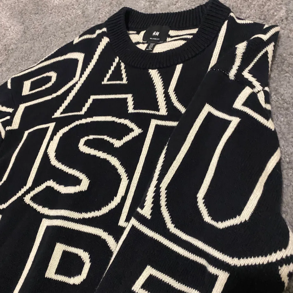 Säljer en svart tröja från H&M med stora vita bokstäver som bildar ordet 'PAUSE'. Tröjan har en avslappnad passform och långa ärmar. Perfekt för en cool och avslappnad stil. Kan kännas lite som oversize!. Neuletakit & Villapaidat.