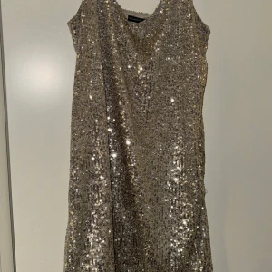 Glittrig klänning från pull&bear - Säljer en glittrig klänning från pull&bear i en snygg guldfärg. Klänningen   har en v-ringad design som ger en elegant look. Perfekt för festliga tillfällen! ✨