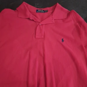 Röd pikétröja från Ralph Lauren - Säljer en klassisk röd pikétröja från Ralph Lauren med broderade loggan på bröstet.