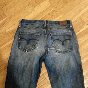 Blå jeans från pepe jeans - Säljer super snygga blå jeans från pepe jeans  med en klassisk femficksdesign och slitningar för en trendig look. Jeansen har 2 hål vid fickorna men det har inte stoppat mig från att använda de. De har en fin 2000-tals model. Priset kan diskuteras. 🫶