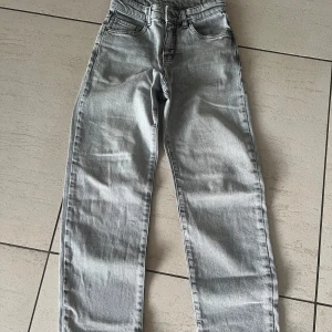 Grå jeans från Kappahl - Snygga grå jeans från Kappahl i storlek 146. De har en klassisk femficksdesign och en rak passform. Perfekta för en avslappnad stil.