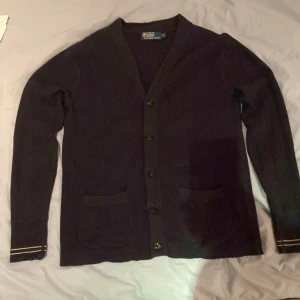 Marinblå kofta från Polo Ralph Lauren - Säljer en stilren svart kofta från Polo Ralph Lauren. Koftan har långa ärmar och knappar framtill. Den har två praktiska fickor och subtila detaljer vid ärmen. Koftan är gjord på 70% bomull och 30% kaschmir.