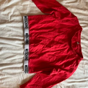 Moschino - Croppad tröja från Moschino i röd, super snygg och i bra skick! Storlek M men skulle säga att den passar bra både S o M