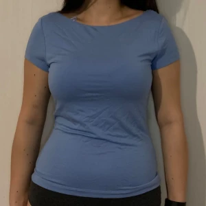 Blå topp med öppen rygg - Säljer en snygg blå topp med korta ärmar och en djup öppen rygg. Perfekt för en stilren och modern look. Toppen är i ett mjukt och bekvämt material.