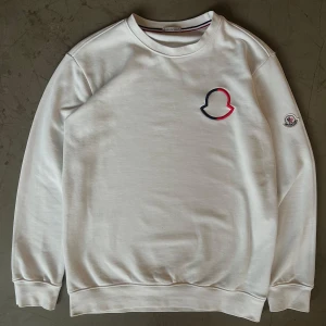 Moncler tröja - Säljer en vit Moncler-tröja i utmärkt skick. Tröjan har endast använts ett fåtal gånger och är som ny.  Storleken passar inte mig längre, så nu får någon annan chansen att använda den. Vid behov skickar jag gärna exakta mått – hör av dig om du är intresserad!   hög kvalitet…