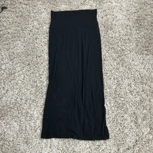 Svart långkjol från Lindex - Snygg svart långkjol från Lindex med en stilren design. Kjolen har en slits baktill som ger extra rörelsefrihet. Perfekt för en elegant look.