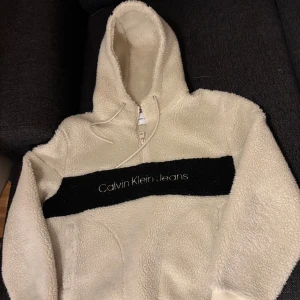 Fluffig Calvin Klein hoodie - Fluffig Calvin Klein hoodie (beige/vit/eggshell) i ny skick, använd endast 2 gånger. Stor i storleken, passar S/M. Mysig och fin och passar bra med många outfits!🤩 Ny pris 1700 (finns på Zalando) Skriv för mer info! Pris kan diskuteras vid snabb affär!😊