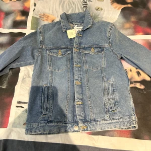 Blå jeansjacka från Lefties - Säljer en klassisk blå jeansjacka från Lefties. Jackan har knappar framtill och två bröstfickor med knappstängning. Perfekt för en avslappnad stil. Helt ny aldrig använt 
