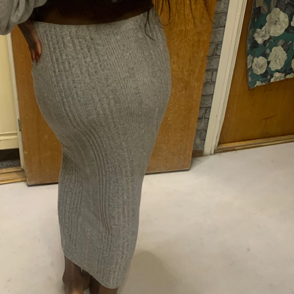 Snygg grå ribbad kjol i tight passform. Kjolen är lång och perfekt för en stilren look. Den är gjord i ett mjukt och stretchigt material som formar sig fint efter kroppen.. Hameet.