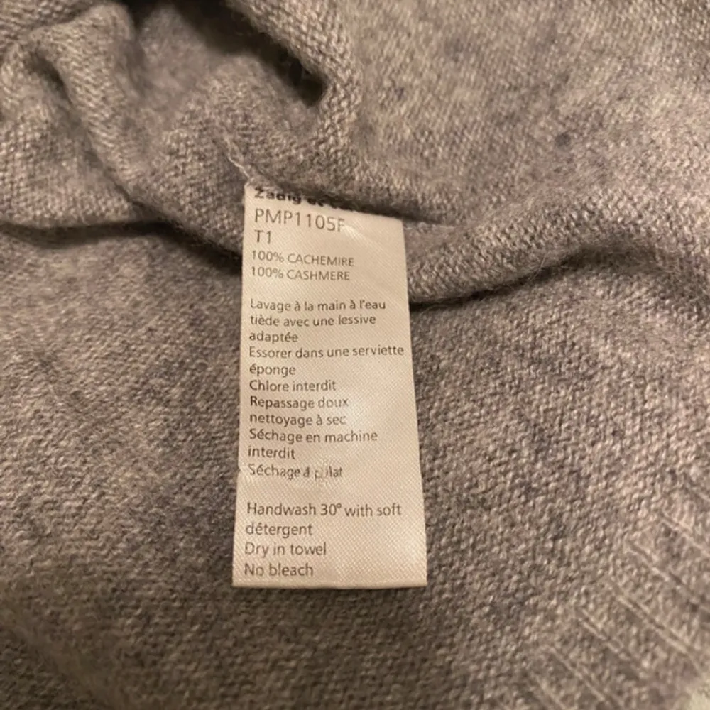 Säljer en elegant grå kashmirtröja från Zadig & Voltaire. Tröjan har en v-ringad design och långa ärmar, perfekt för en stilren look. Tillverkad i 100% kashmir för en lyxig och mjuk känsla. Passar utmärkt för kyligare dagar.. Neuletakit & Villapaidat.