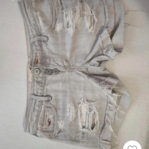 Grå jeansshorts från Hollister - !Lånade bilder! Fina ljusgrå jeansshorts från Hollister med as snygga slitna detaljer på🤍Strl w24/S men tror även att de kan passa M. Säljer då de är för stora, tvättas såklart innan de blir skickade. Midjemått 37 cm tvärs över. Säg gärna till för fler bilder eller frågor❣️