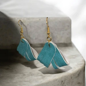 Turkosa örhängen med fransar - Unika turkosa örhängen av konstläder, med fransar och guldfärgade krokar. De har en modern design med flera lager som ger en snygg effekt. Perfekta för att ge en färgklick till din outfit.