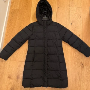 Svart dunjacka från Lager 157 - Säljer en svart lång dunjacka från Lager 157. Storlek 160 men passar mig som brukar ha xs och är 158 cm. Tillverkad i 100% polyester vilket gör den både varm och lätt. Fint skick förutom lite avskaft på dragkedjan (se sista bild) 