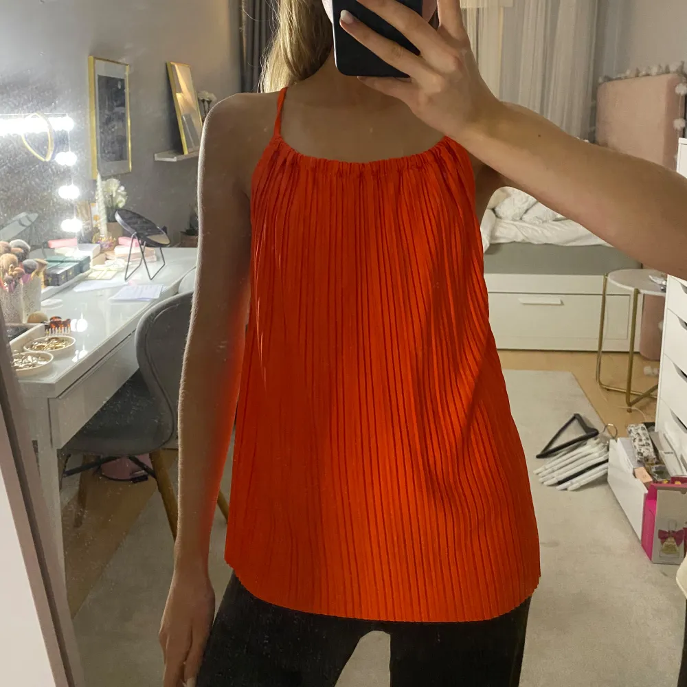 Säljer en snygg orange topp med tunna axelband och öppen rygg. Den är aldrig använd och har prislappen kvar!. Yläosat.
