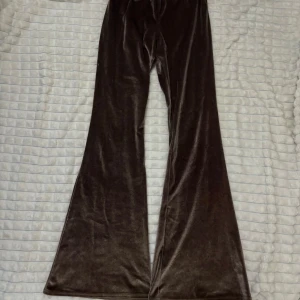 Bruna sammet byxor - Snygga bruna byxor i mjuk sammet med en elegant bootcut-stil. Perfekta för att ge en touch av glamour till din outfit. De har en hög midja som ger en smickrande passform.