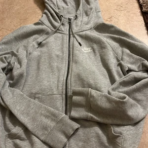 Grå hoodie från Nike - Jätte snygg och bekväm kofta från Nike. Köpt för 800 kr men säljer billigt efter den inte kommer till användning