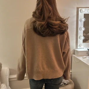 Beige stickad tröja - Säljer en mysig beige stickad tröja med långa ärmar och ribbade kanter. Perfekt för kyliga dagar och enkel att matcha med jeans eller kjol. Hör av dig vid intresse!