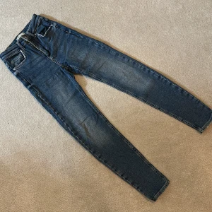 Blå jeansbyxor - Snygga blå jeansbyxor med en tight passform. De har en klassisk design med fem fickor och knappgylf. Perfekta för en stilren look.