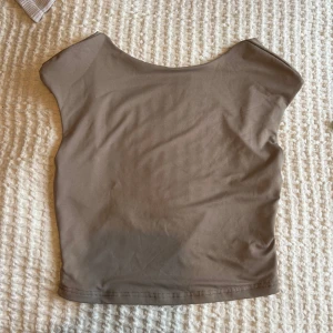 Beige ärmlös topp - Säljer en stilren beige ärmlös topp i ett mjukt och stretchigt material. Perfekt för en minimalistisk look. Toppen har en rund halsringning och en enkel design som gör den lätt att matcha med olika outfits.