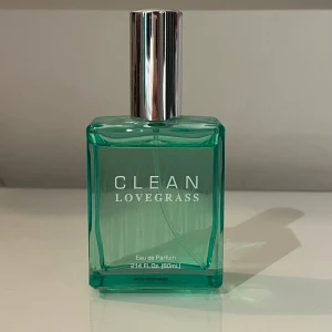 Clean Lovegrass Eau de Parfum - Säljer en fräsch och modern parfym från Clean, Lovegrass. Flaskan är i en stilren fyrkantig design med en klar grön färg och en silverfärgad kork. Innehåller 60 ml Eau de Parfum. Använt lite!!