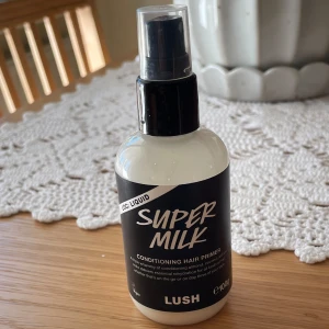 Super Milk Conditioning Hair Primer från Lush - Säljer en Super Milk Conditioning Hair Primer från Lush. Den kommer i en vit flaska med svart etikett och har en praktisk spraypump. Produkten är vegansk och innehåller en blandning av vårdande ingredienser för att ge håret fukt och skydd. Perfekt för att använda som en leave-in conditioner.